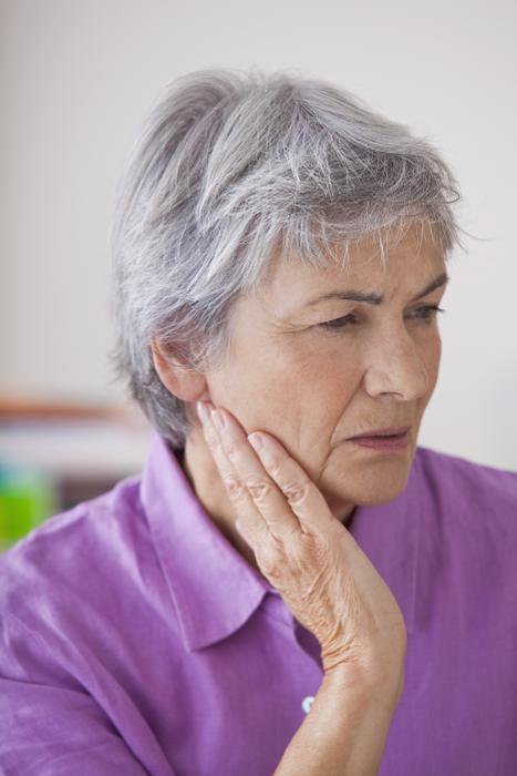 older woman in pain holding jaw | tmj treatment avondale 