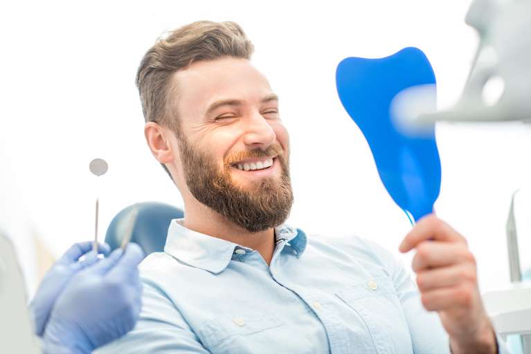 A man smiling while checking his teeth after a cosmetic dentistry in Auckland, Avondale