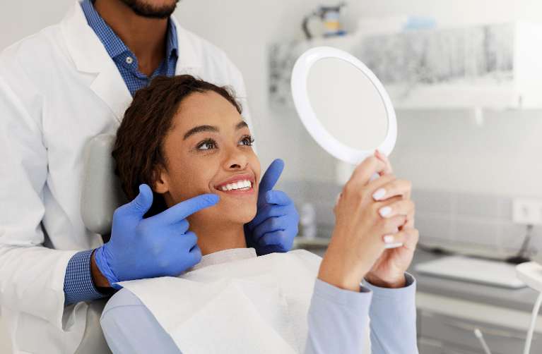 A woman smiling while checking her teeth after a Professional Teeth Whitening treatment in Avondale 